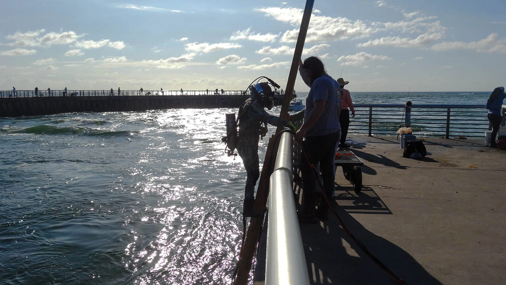Commercial diver preparing for water entry with surface-support equipment staged on deck