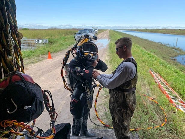 ADCI-certified commercial diver suiting up with surface support tender on a Florida canal