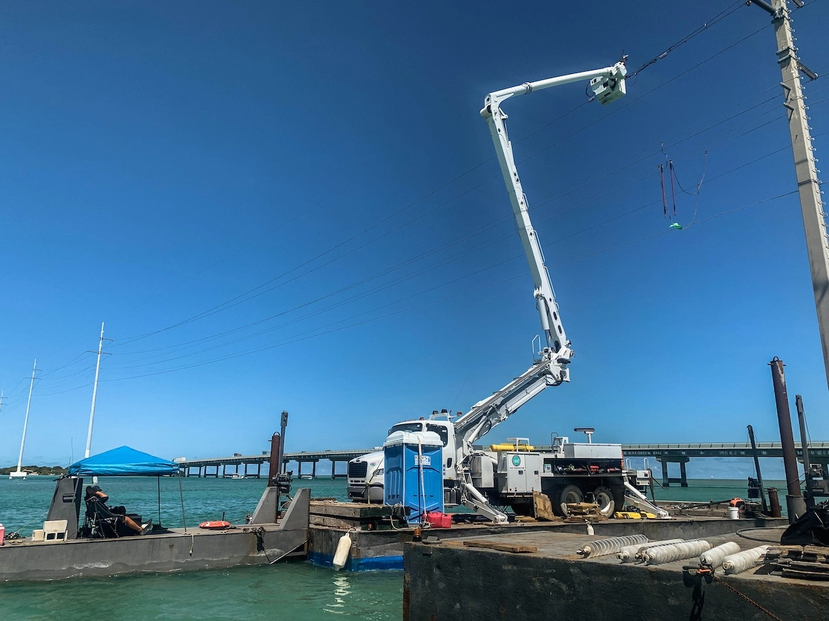 Marine construction barge with crane performing utility line work over water
