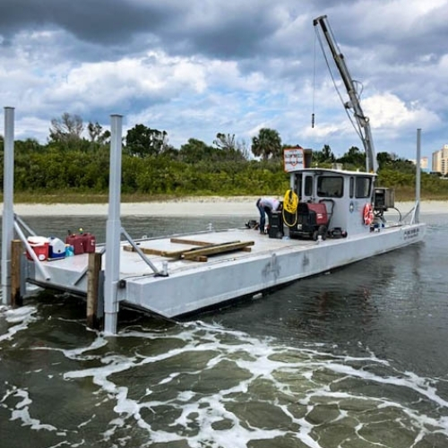 Marine construction barge with mounted crane on a Florida waterfront construction site
