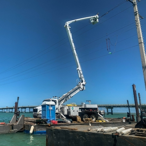 Marine construction barge with crane performing utility line work over water