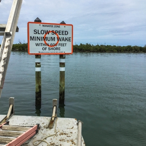 Manatee Zone slow-speed minimum-wake sign marking a Florida waterway adjacent to a marine construction project