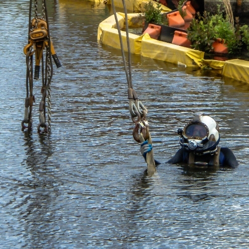 Commercial diver performing underwater rigging beside containment booms