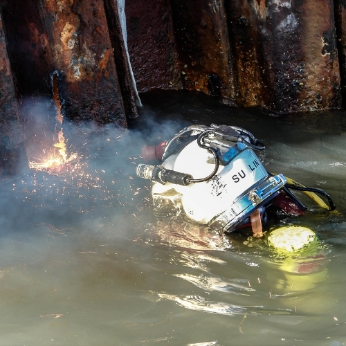 Commercial diver performing underwater welding on a corroded steel structure