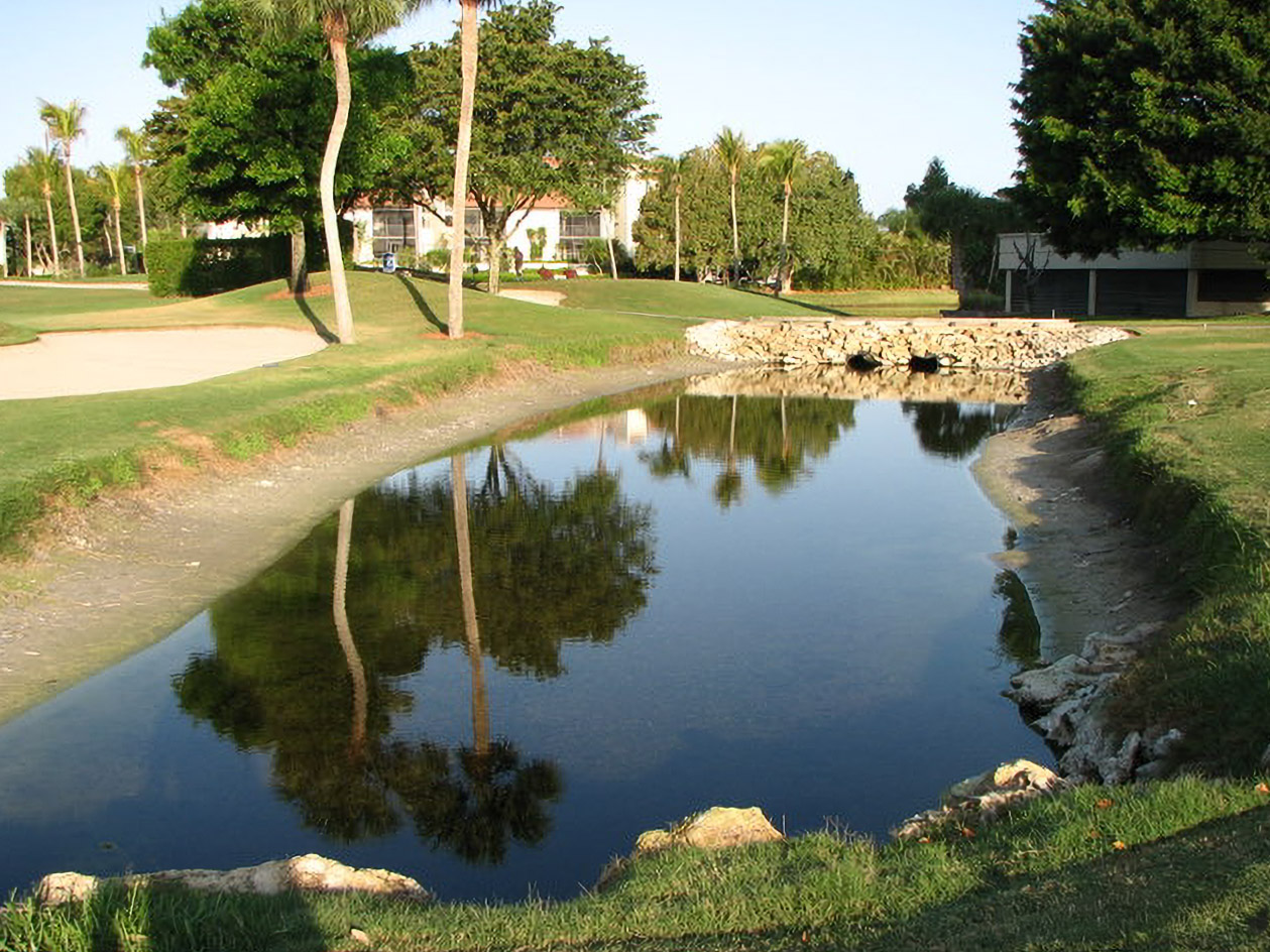 Golf course pond with riprap and sand bunker before restoration at Yacht, Golf & Tennis