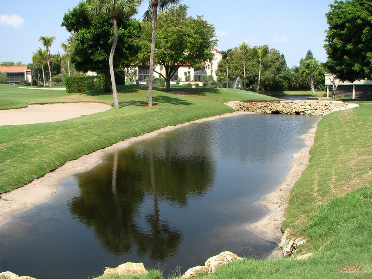 Restored pond reflecting palms and fairways at Yacht, Golf & Tennis after bank stabilization