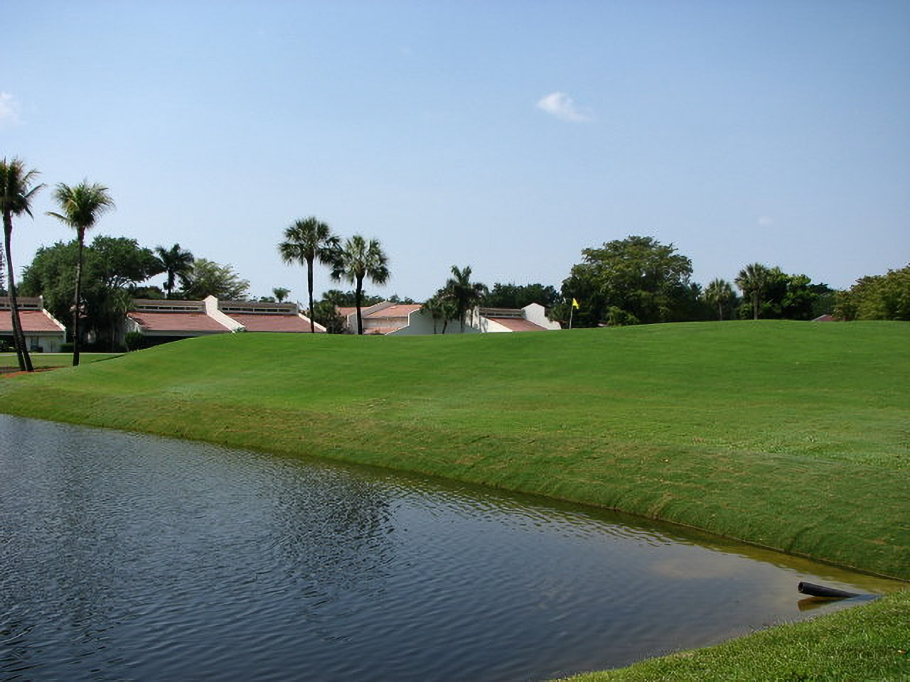 Restored green and pond bank at Yacht, Golf & Tennis with clubhouse villas beyond