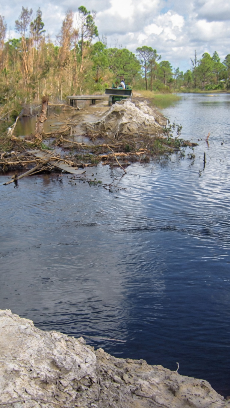 Colony Ranch lake with rocky outcrop and storm-damaged trees