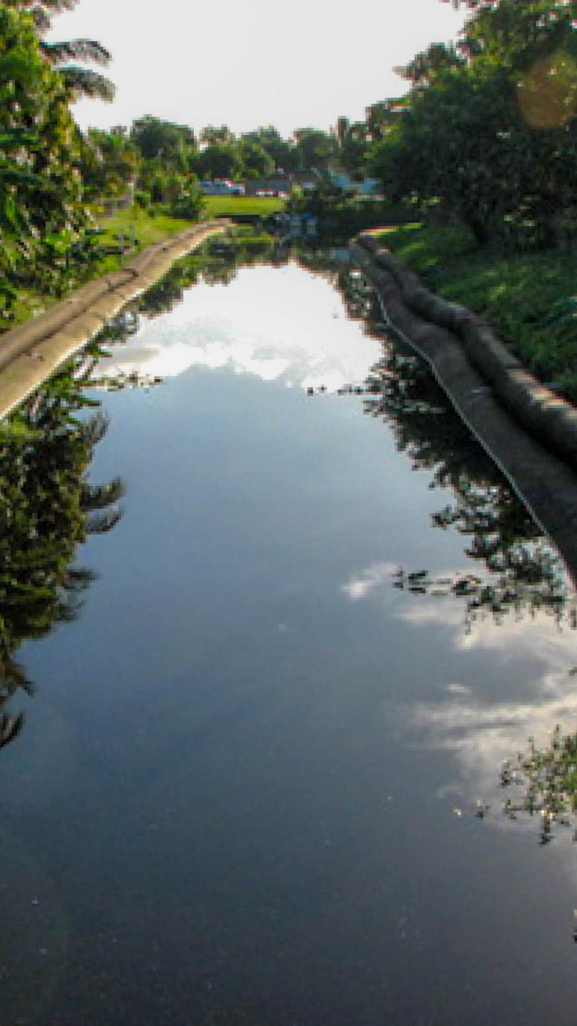 Long view down a Margate canal during restoration, with mirror-still water and Geo Tube exposed on both banks