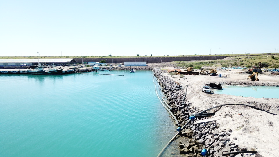 Coastal infrastructure project with rip-rap shoreline reinforcement and earth-moving equipment along a Florida waterway